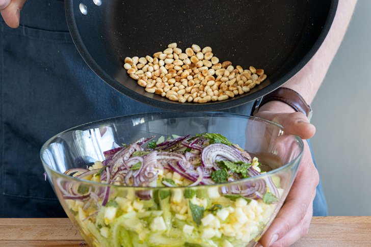 Pinienkerne in den Salat geben