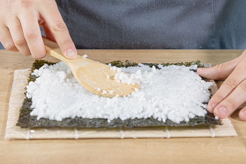 Sushi Reis auf dem Noriblatt verteilen