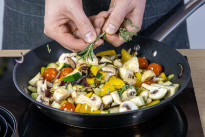 Kräuter in die vegetarische Gemüsepfanne zupfen