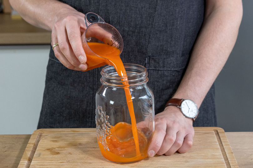 Karottensaft in ein Glas geben
