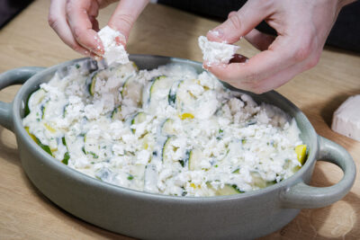 Vegetarischer Kartoffel-Zucchini-Auflauf mit Feta garnieren