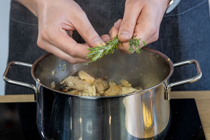 Kräuter in die Pilzsuppe zupfen