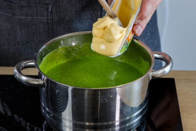 Schmelzkäse in die Spinatsuppe geben