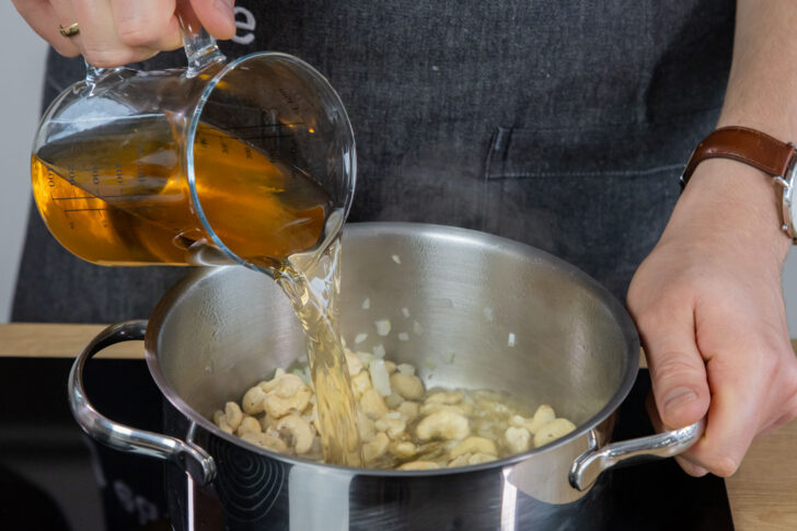 Gemüsebrühe zu den Cashews gießen