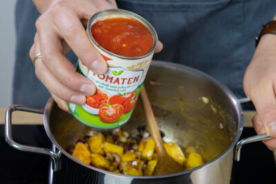 Gehackte Tomaten in den Topf geben