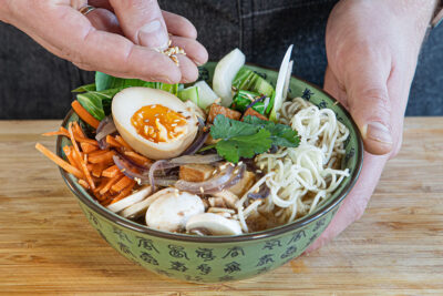 vegetarische Mido-Ramen mit Ei, Koriander und Sesam garnieren