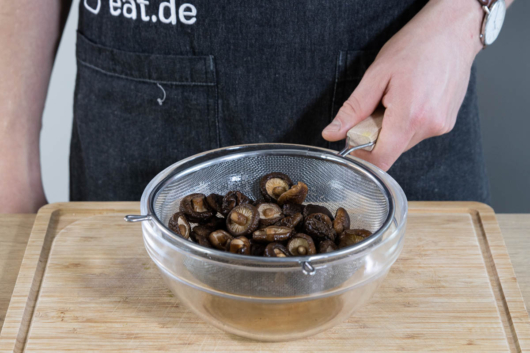Die eingeweichten Shiitake Pilze für die vietnamesischen Sommerrollen abtropfen lassen.