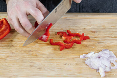 Schalotten und Paprika in Streifen schneiden