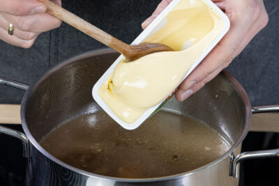 Schmelzkäse zur Käsesuppe mit Hackfleisch und Lauch geben