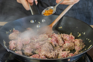 Hackfleisch mit Chiliflocken würzen