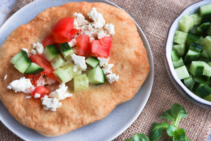 Langos Belag mit Feta, Gurke und Tomate.