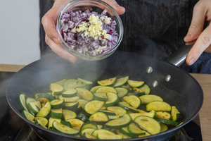 Zwiebel und Knoblauch zur Zucchini geben