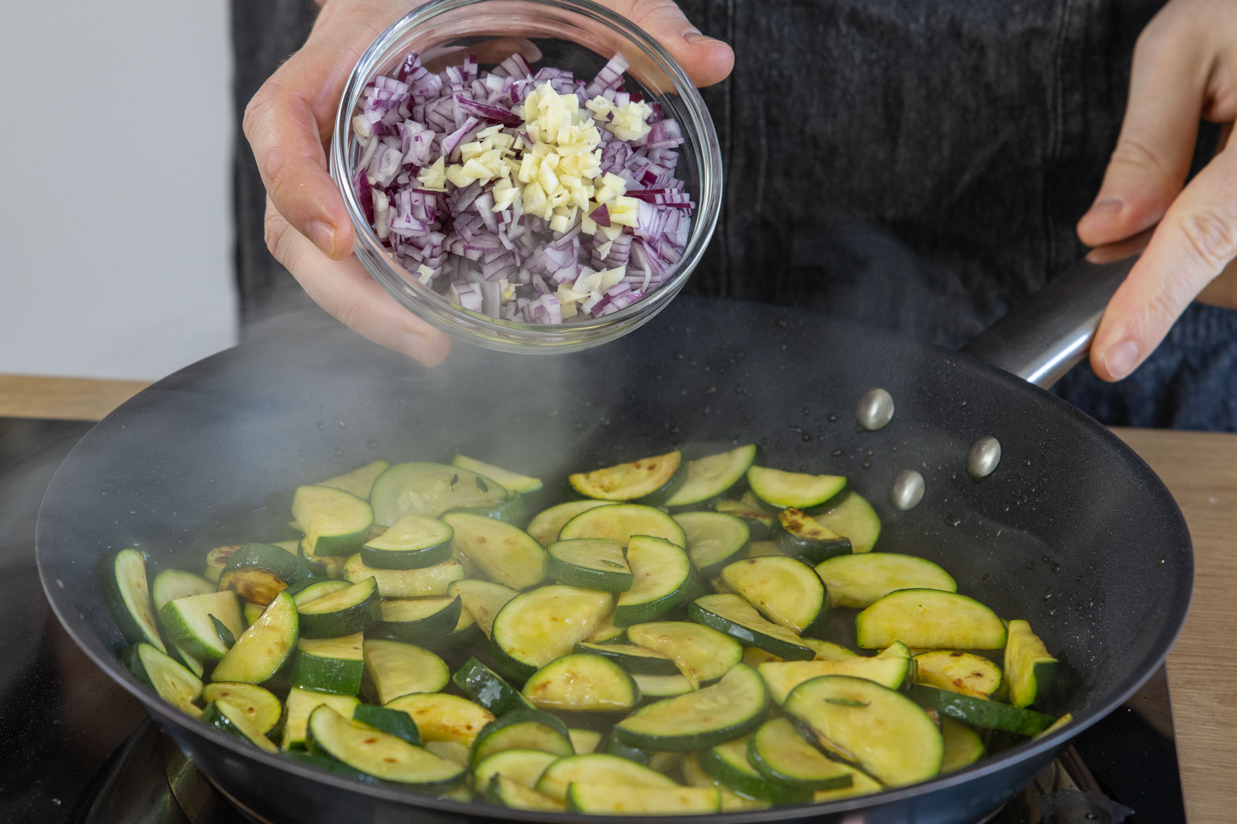 Zwiebel und Knoblauch zur Zucchini geben