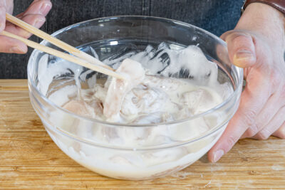 Hähnchen mit dem Backteig vermengen