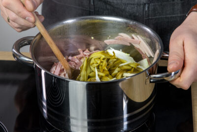 Wurst, Zwiebeln und Gurken im Topf anbraten