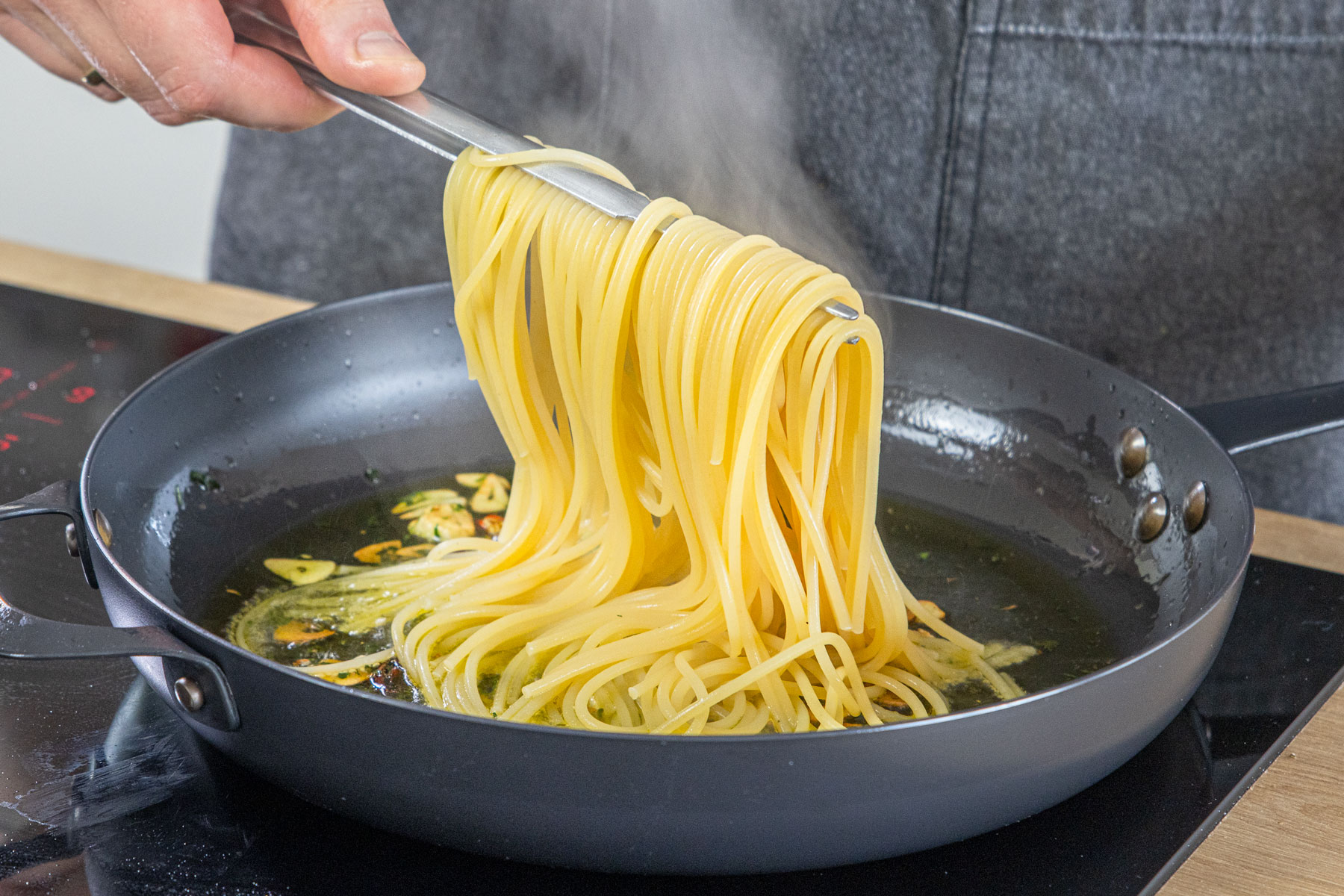 Spaghetti in die Pfanne geben