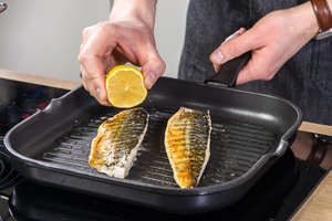Zitrone über den Fisch pressen
