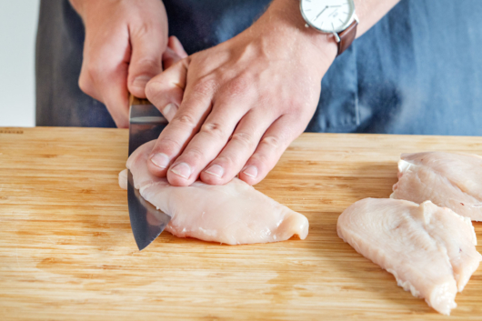 Die Hühnerbrust vorsichtig in dünne Scheiben für das Paprikaschnitzel schneiden.