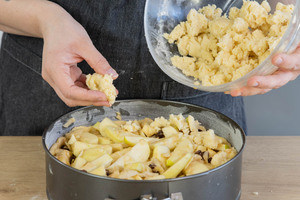 Streusel auf dem einfachen Apfelkuchen verteilen