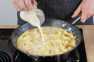 Sahne zur Gnocchi-Pfanne mit Gorgonzola gießen