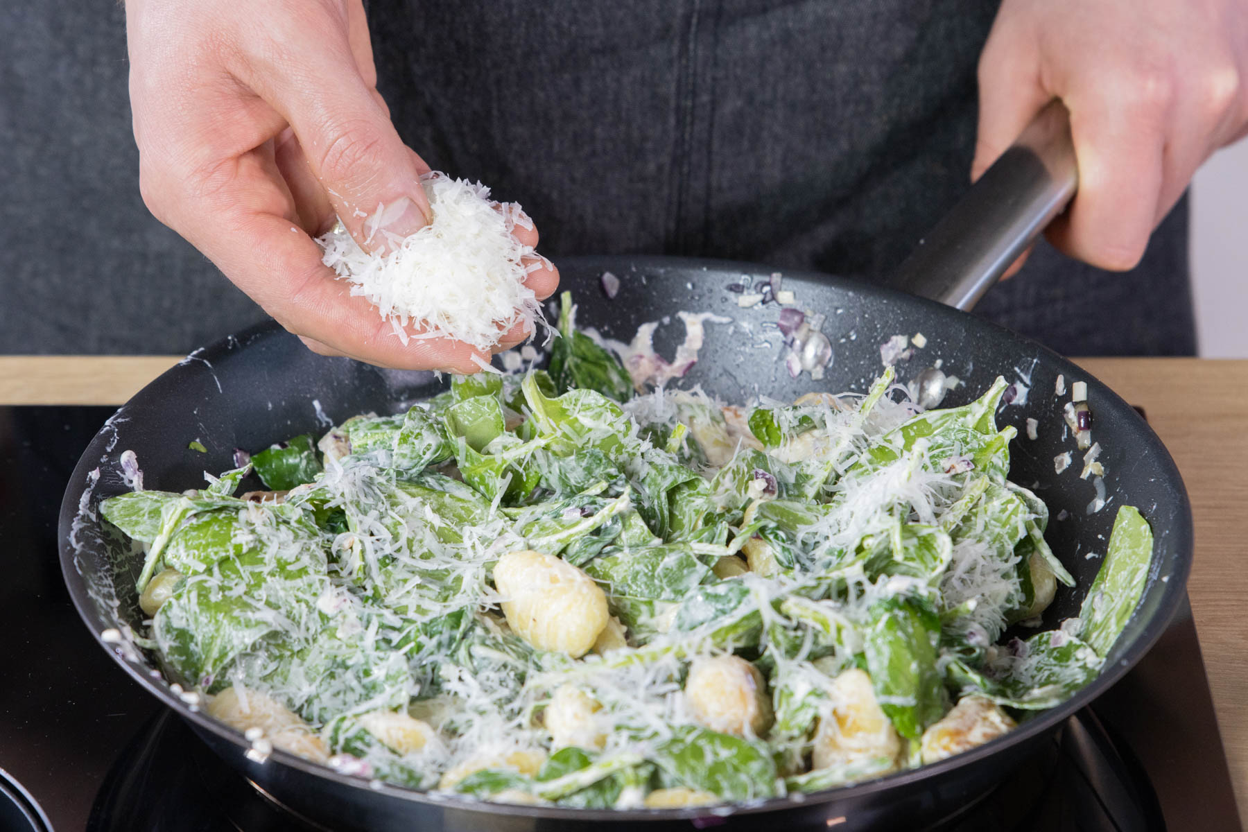 Pecorino zu der Gnocchi-Pfanne geben