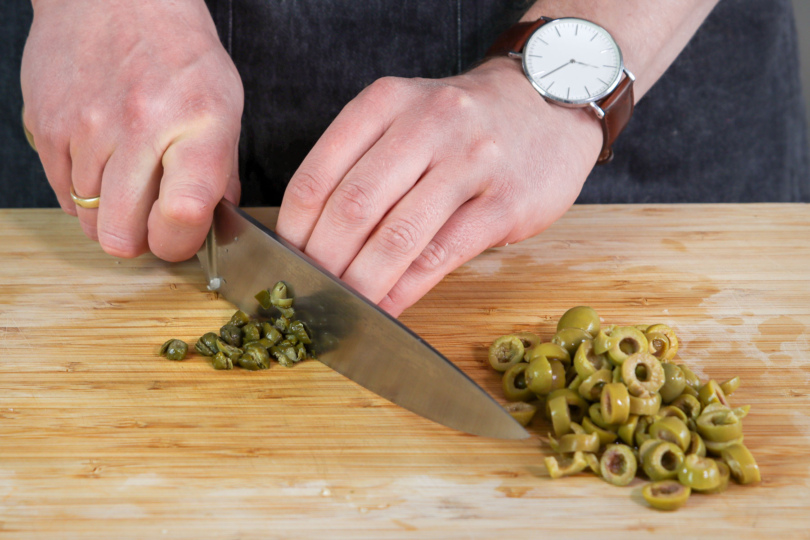 Oliven und Kapern klein schneiden.