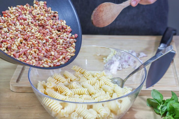 Schinken und Pinienkerne zum Italienischer Nudelsalat geben
