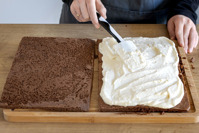 Creme auf dem Milchschnittenkuchen verteilen