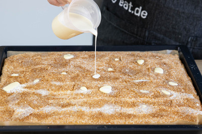 Sahne über den Kokoskuchen gießen.