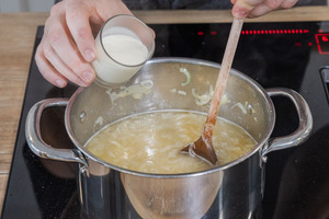 Sahne zur Zwiebelsuppe gießen