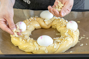Mandeln und Hagelzucker auf dem Osterkranz mit frischer Hefe verteilen