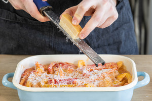 Parmesan über das Paprika-Sahne-Hähnchen reiben.