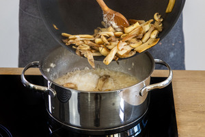 Die gebratenen Pilze in die Masse für das einfache Pilzrisotto geben.
