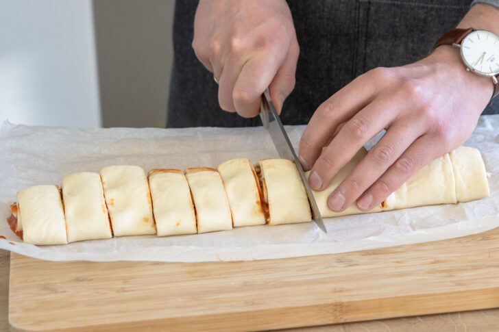 gerollten Pizzateig in Schnecken schneiden