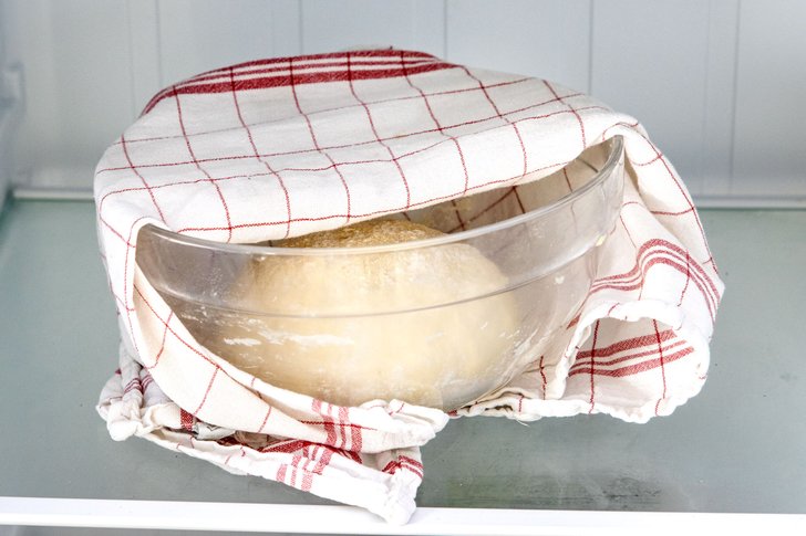 Pizzateig abgedeckt im Kühlschrank