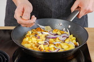 Majoran an geröstete Kartoffeln geben