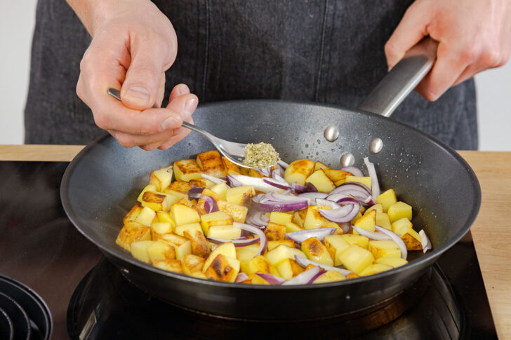 Majoran an geröstete Kartoffeln geben