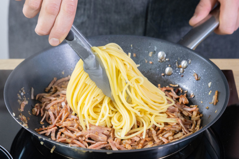 Spaghetti in die Pfanne geben