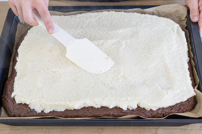 Kokoscreme auf Kuchenboden streichen