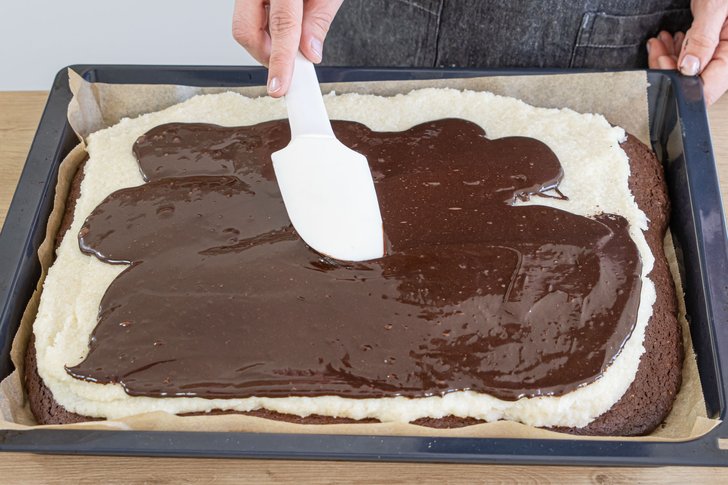 Schokoguss auf Schoko Kokos Kuchen verteilen