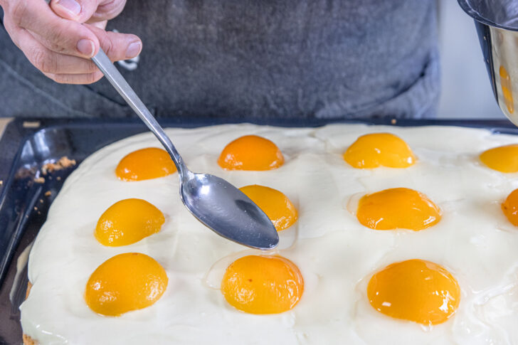 Tortenguss über den Spiegeleikuchen vom Blech geben
