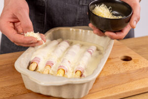 Käse auf den Spargel-Schinken-Röllchen verteilen