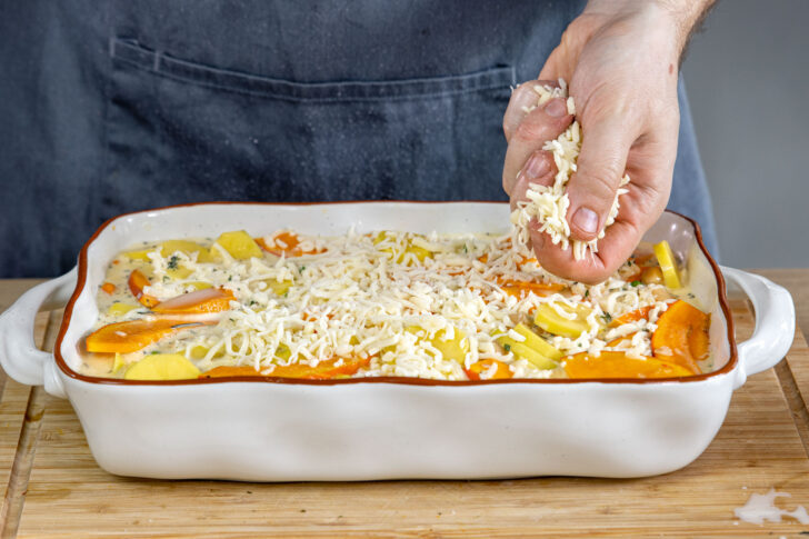 Käse über den vegetarischen Kartoffelauflauf geben