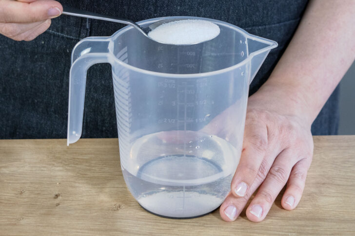 Zucker in lauwarmes Wasser geben