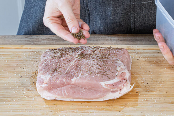 Schweinebraten mit Salz, Pfeffer und Kümmel einreiben