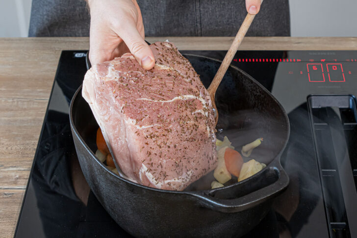Schweinebraten in den Bräter legen