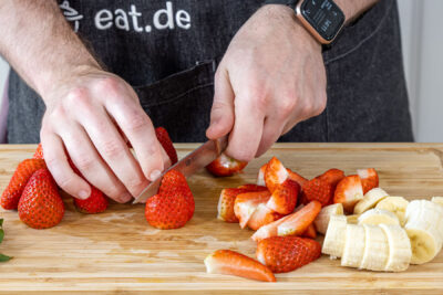 Erdbeeren und Bananen in Stücke schneiden