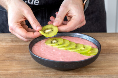 Kiwi auf Smoothie Bowl legen