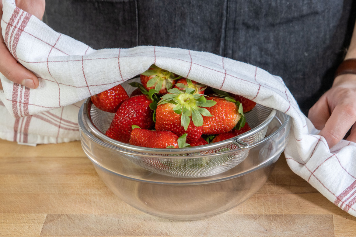 Erdbeeren im Sieb mit Tuch abdecken