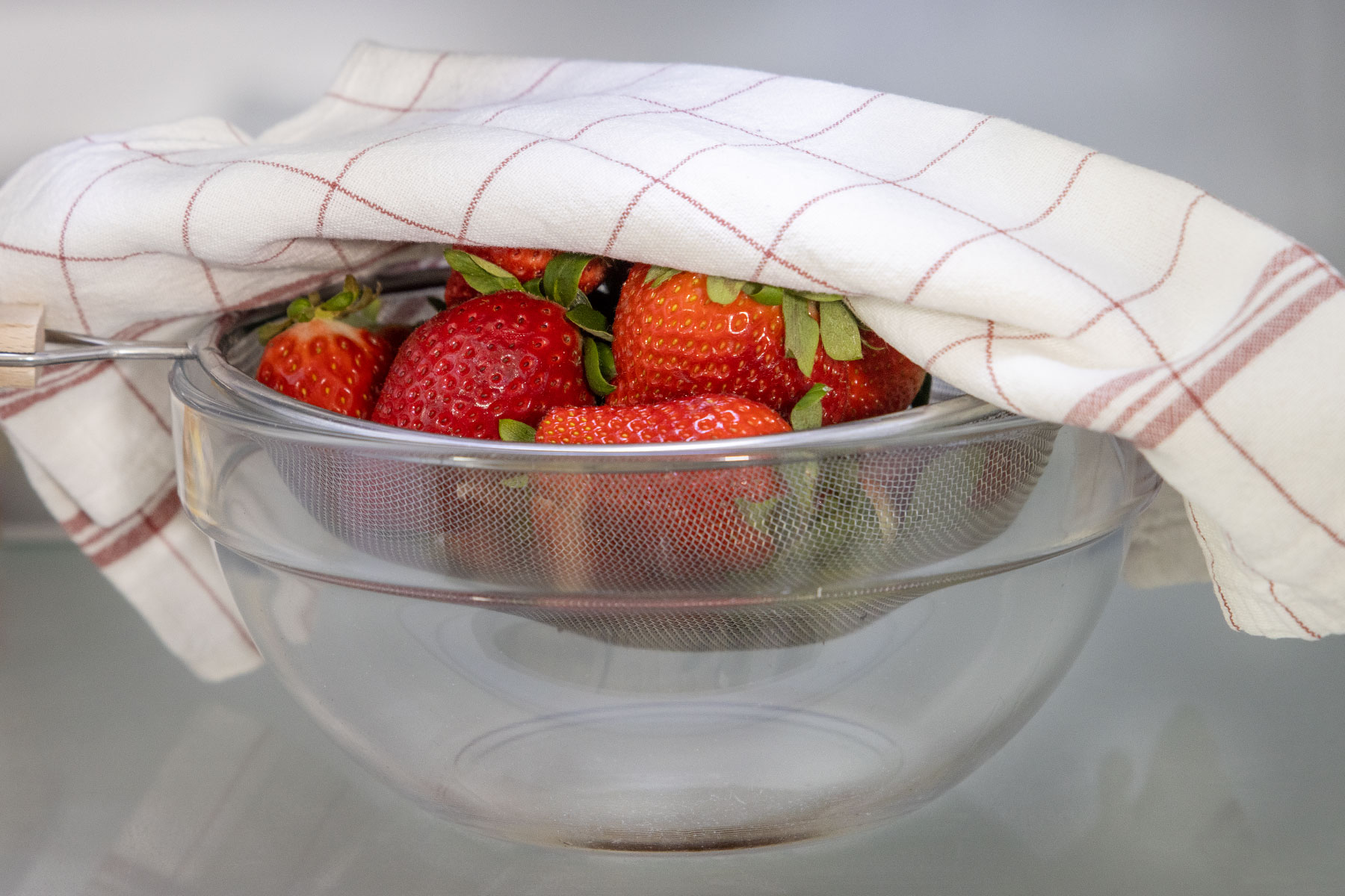 Erdbeeren abgedeckt in Sieb im Kühlschrank